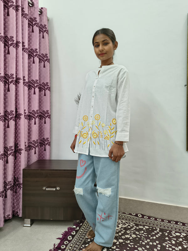 Model wearing white cotton short kurti with yellow floral embroidery and button-down front standing indoors