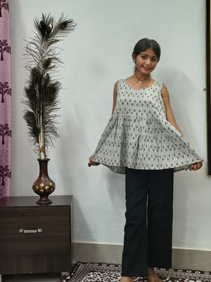 Woman wearing light grey floral print sleeveless short cotton kurti standing indoors