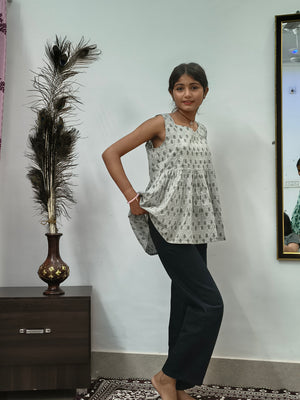 Woman wearing light grey floral print sleeveless short cotton kurti standing indoors