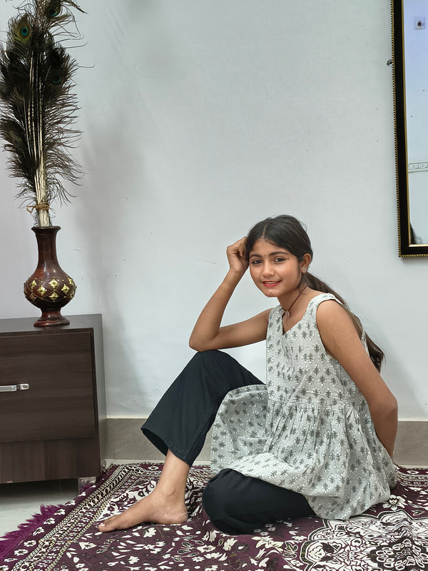Woman wearing light grey floral print sleeveless short cotton kurti standing indoors