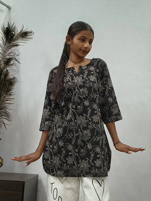 Model wearing black cotton short kurti with white floral vine print indoors
