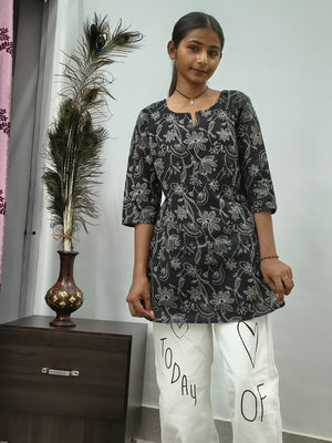 Model wearing black cotton short kurti with white floral vine print indoors