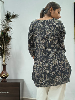 Model wearing black cotton short kurti with white floral vine print indoors
