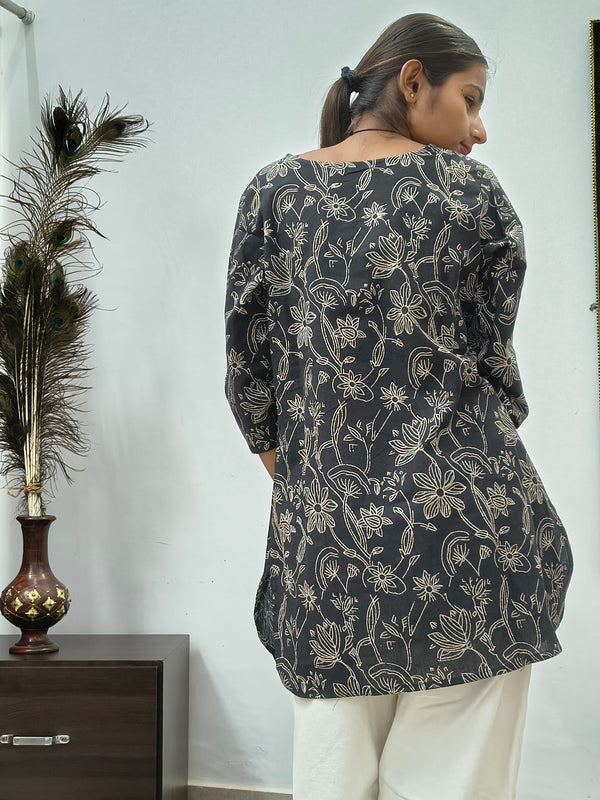 Model wearing black cotton short kurti with white floral vine print indoors