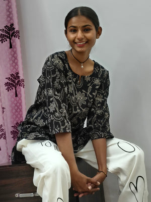 Model wearing black cotton short kurti with white floral vine print indoors