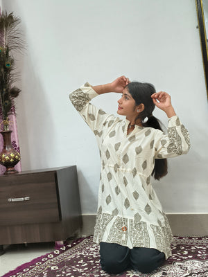 Model wearing ivory block print tiered short cotton kurti with gold motifs standing indoors