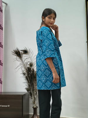 Model wearing turquoise blue geometric print short cotton kurti with wide sleeves indoors