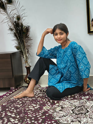 Model wearing turquoise blue geometric print short cotton kurti with wide sleeves indoors