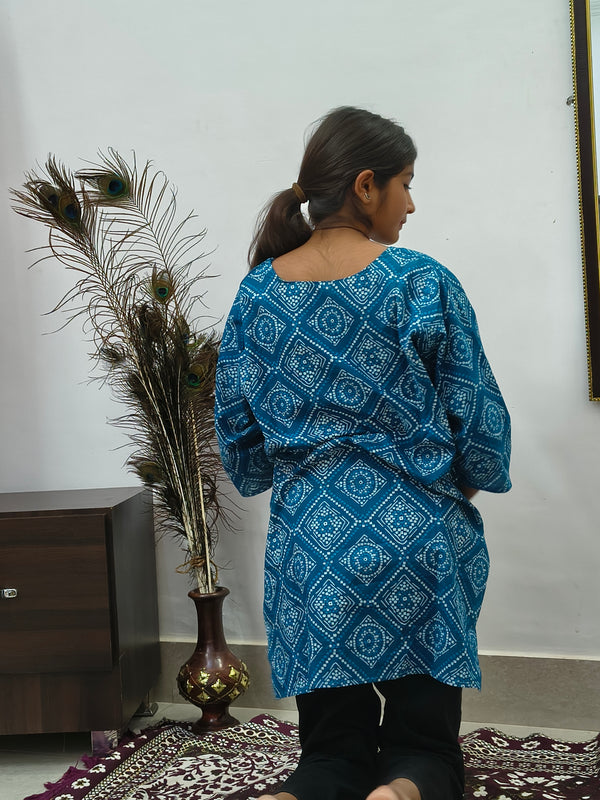 Model wearing teal blue geometric print cotton short kurti with wide sleeves indoors