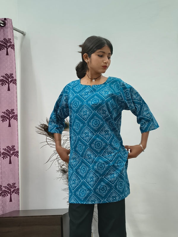 Model wearing turquoise blue geometric print short cotton kurti with wide sleeves indoors