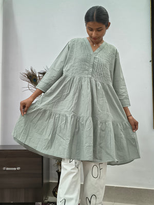 Model wearing sage green tiered cotton tunic kurti with v-neck and three quarter sleeves indoors