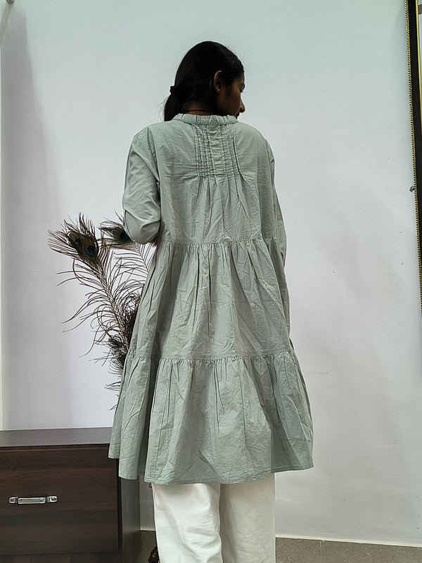 Model wearing sage green tiered cotton tunic kurti with v-neck and three quarter sleeves indoors