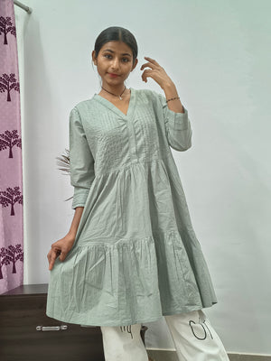 Model wearing sage green tiered cotton tunic kurti with v-neck and three quarter sleeves indoors