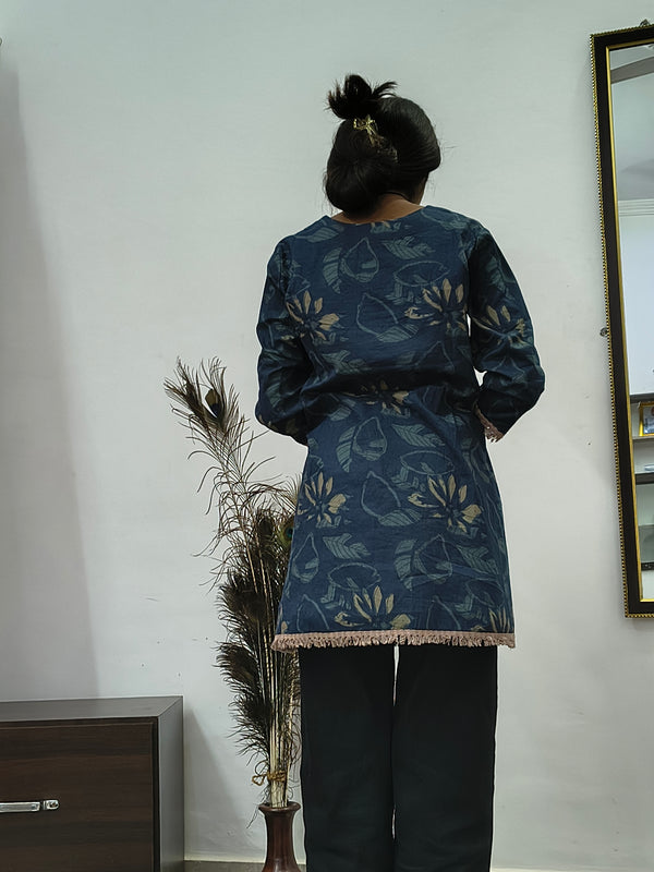 Woman wearing navy blue floral embroidered short cotton kurti with three quarter sleeves standing indoors