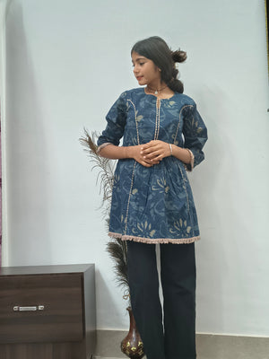 Woman wearing navy blue floral embroidered short cotton kurti with three quarter sleeves standing indoors