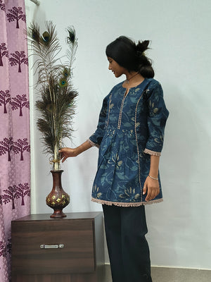 Woman wearing navy blue floral embroidered short cotton kurti with three quarter sleeves standing indoors