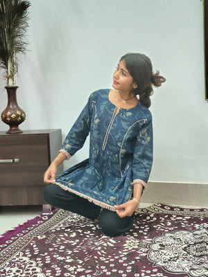 Woman wearing navy blue floral embroidered short cotton kurti with three quarter sleeves standing indoors