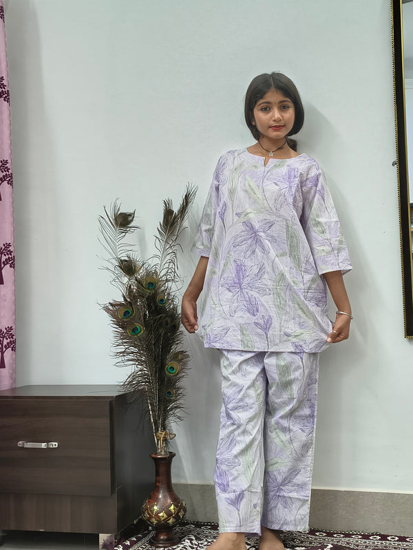 Woman wearing white cotton lavender leaf print co-ord set with matching top and pants indoors