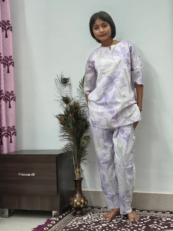 Woman wearing white cotton lavender leaf print co-ord set with matching top and pants indoors