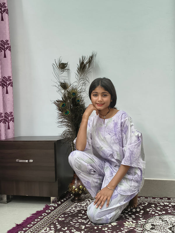 Woman wearing white cotton lavender leaf print co-ord set with matching top and pants indoors