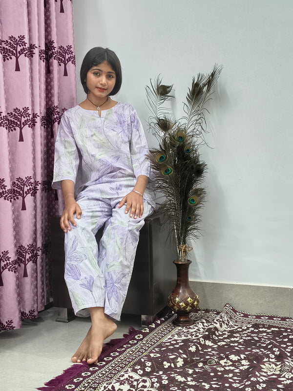 Woman wearing white cotton lavender leaf print co-ord set with matching top and pants indoors