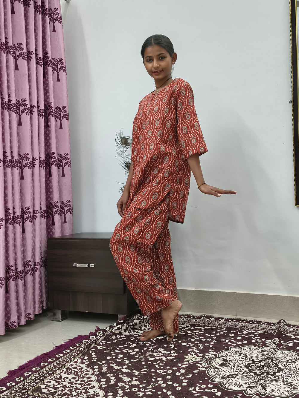 Woman wearing red mandala print cotton corset style kurta set with white block print palazzo pants in indoor setting
