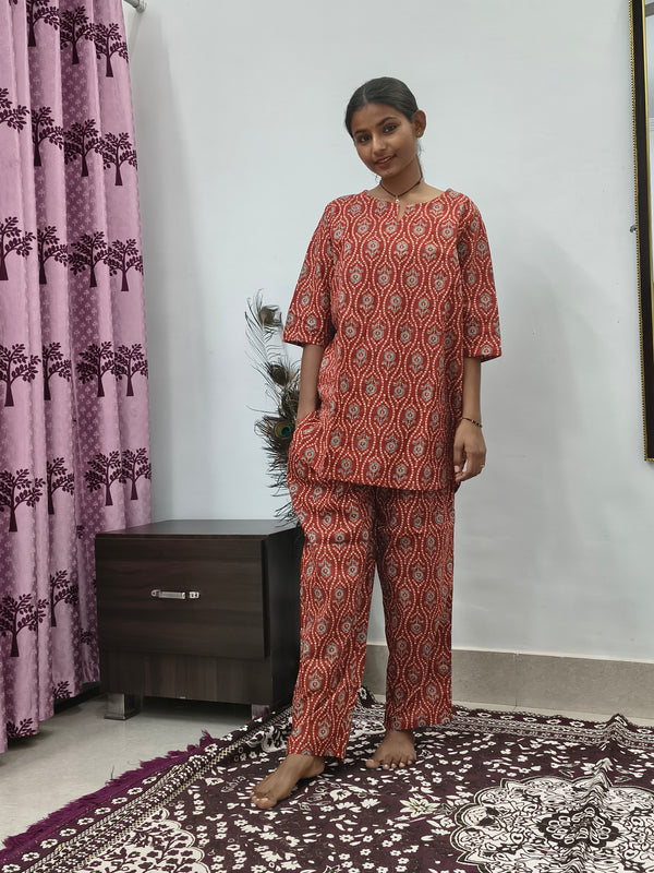 Woman wearing red mandala print cotton corset style kurta set with white block print palazzo pants in indoor setting