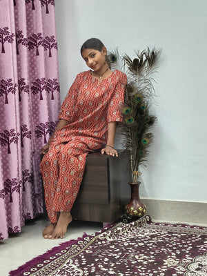 Woman wearing red mandala print cotton corset style kurta set with white block print palazzo pants in indoor setting