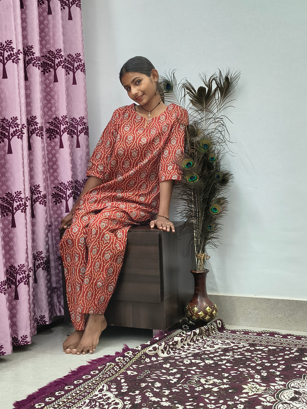 Woman wearing red mandala print cotton corset style kurta set with white block print palazzo pants in indoor setting